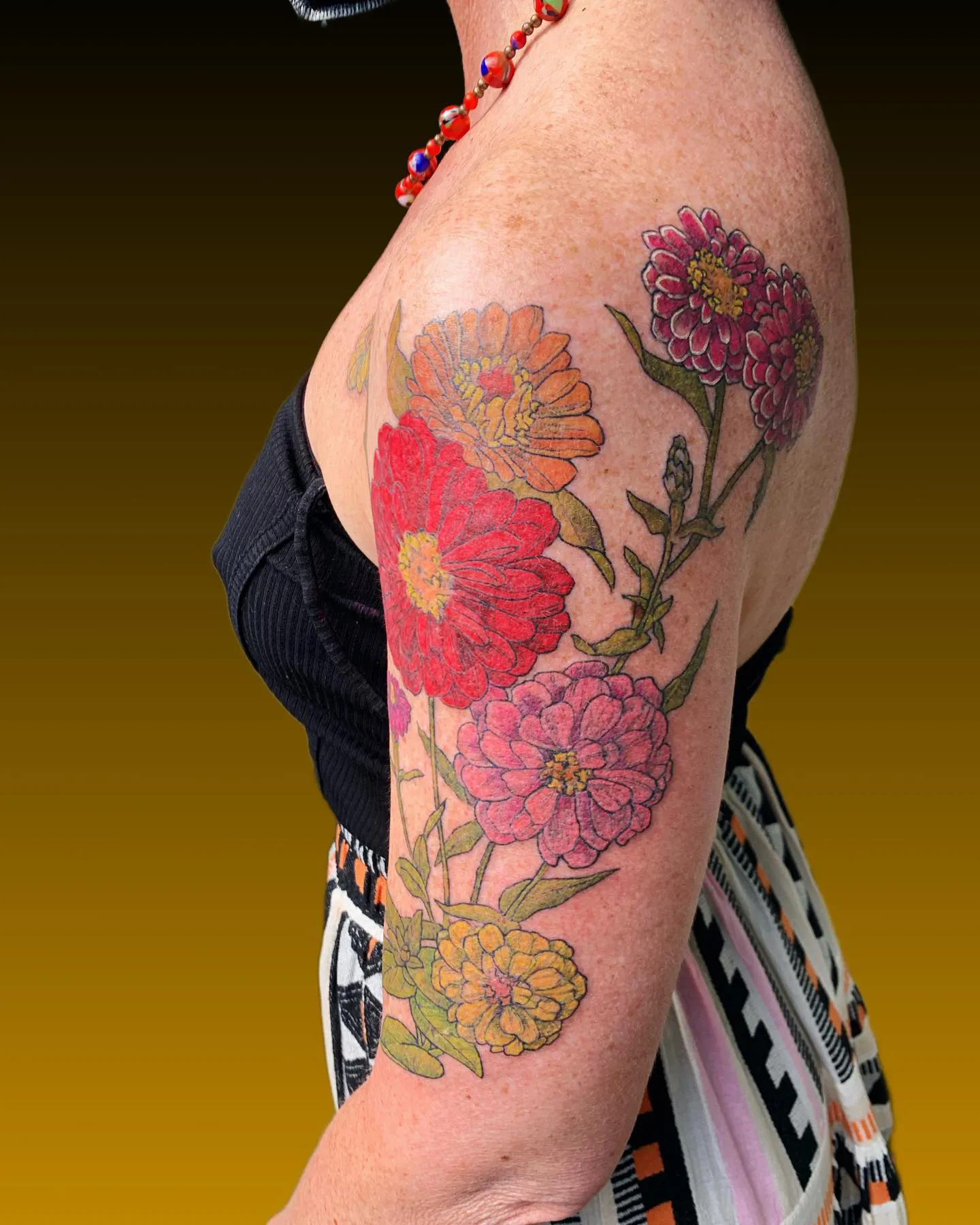 Arm tattoo with delicate zinnia flowers