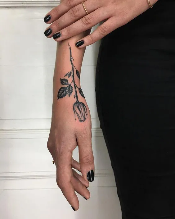 Artistic long-stem rose tattoo on the hand side