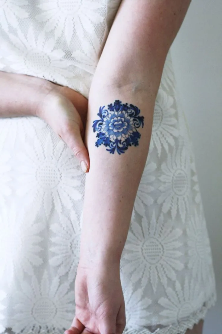 Blue Zinnia flower tattoo on forearm