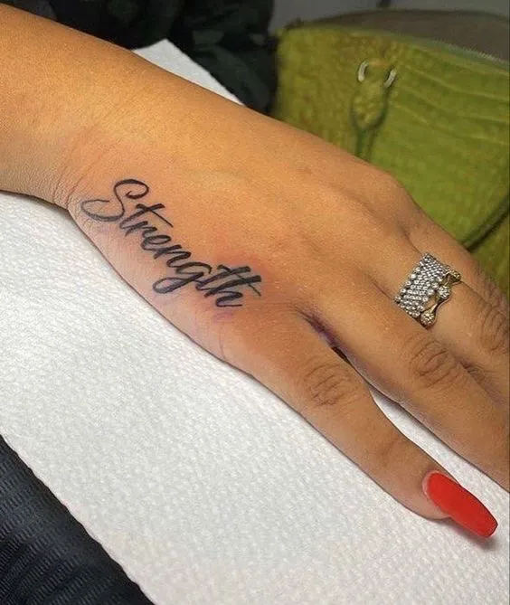 Cursive word tattoo design on hand side for style