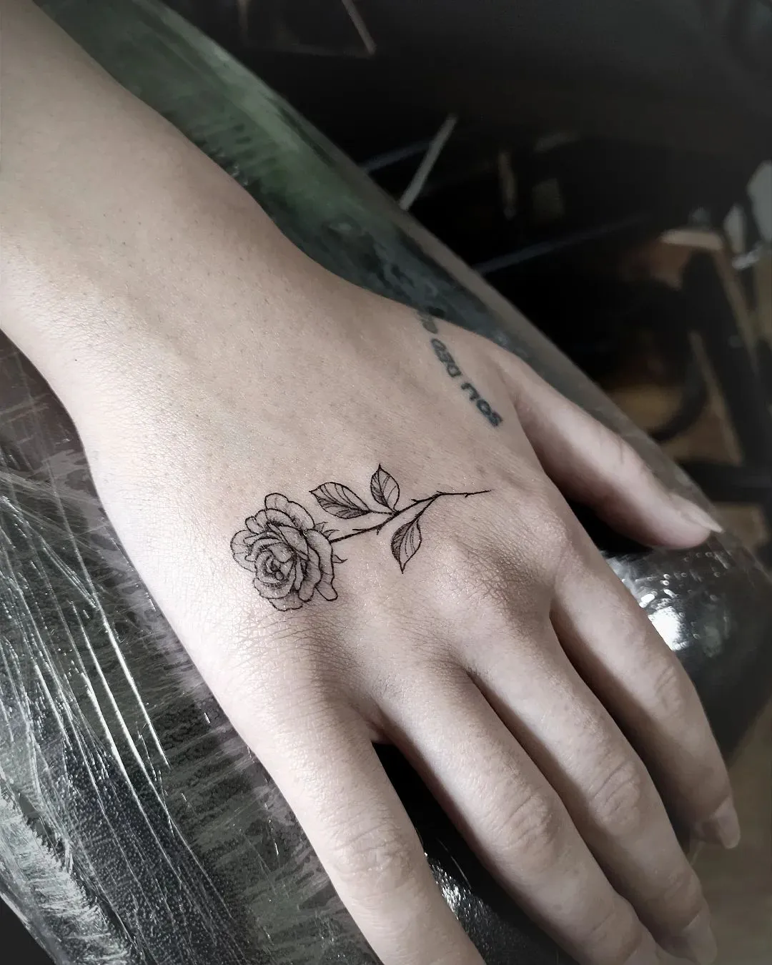 Delicate rose outline as girly side of hand tattoo designs