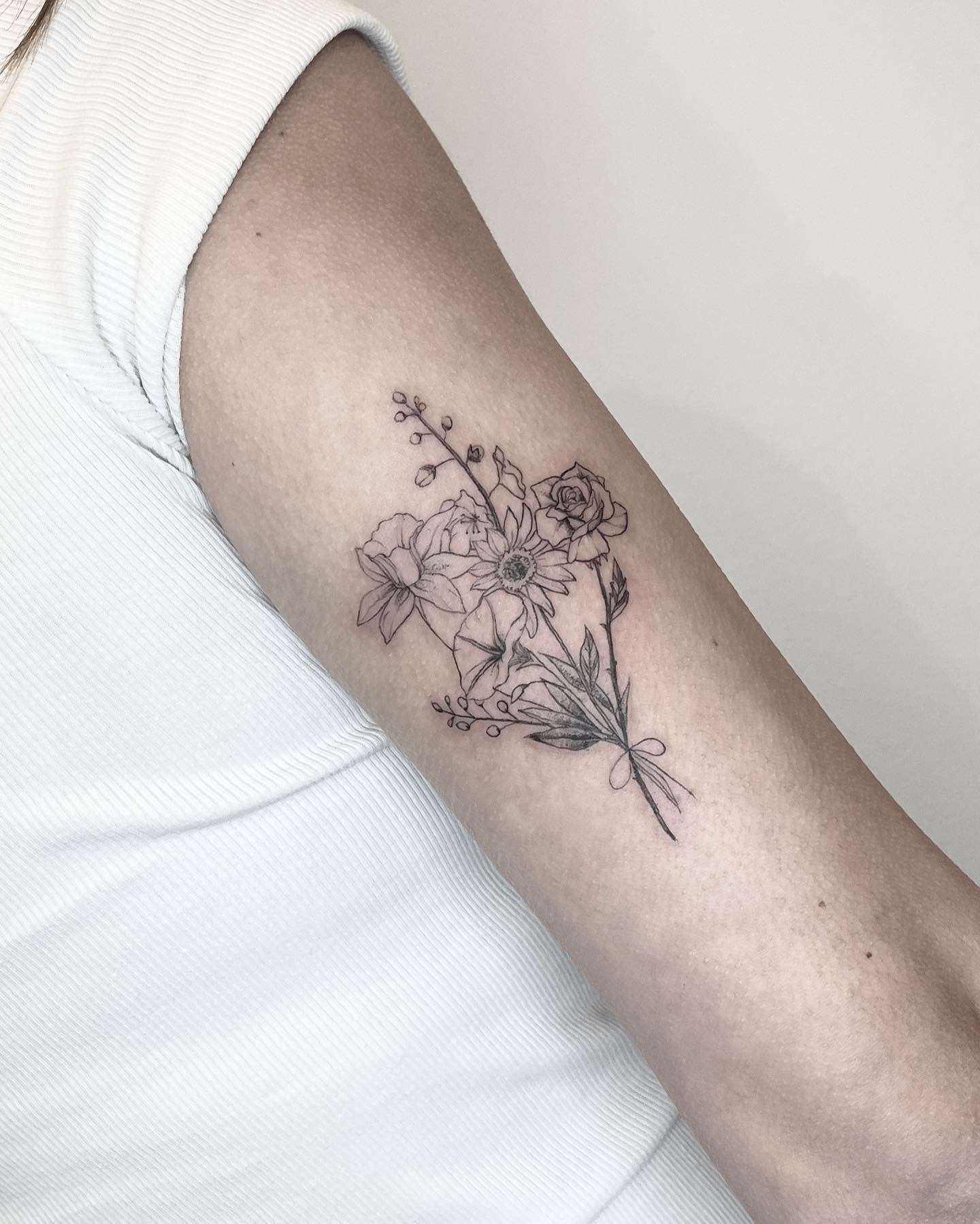 Elegant floral arrangement tattoo on forearm