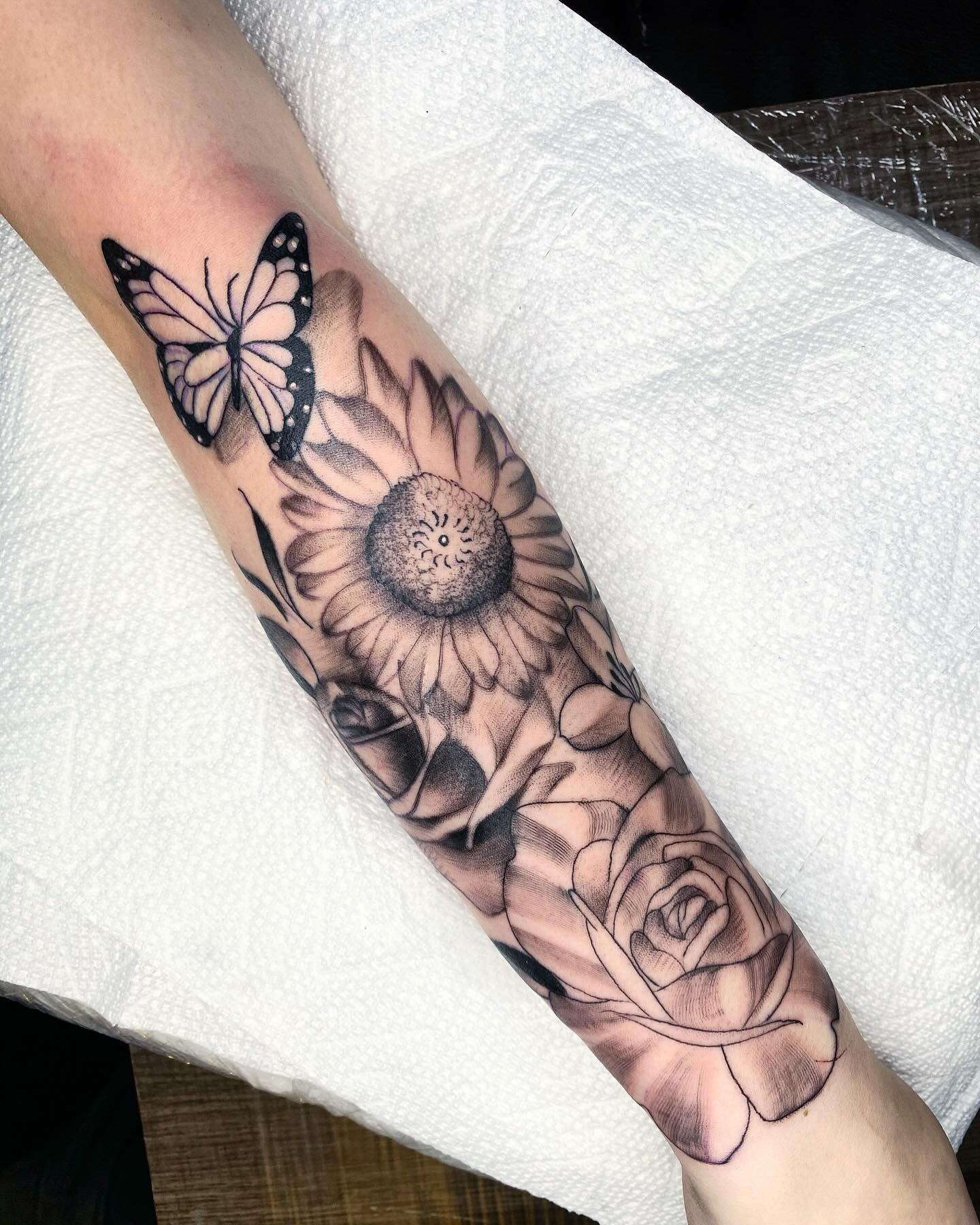 Floral forearm tattoo with a detailed butterfly