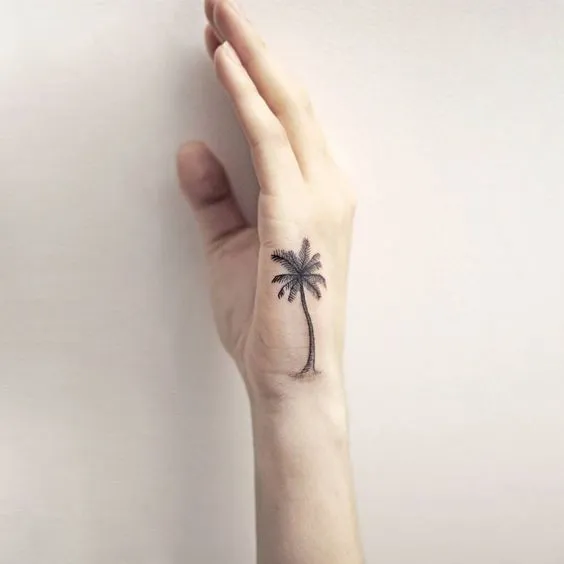 Palm tree silhouette on the side of hand tattoo