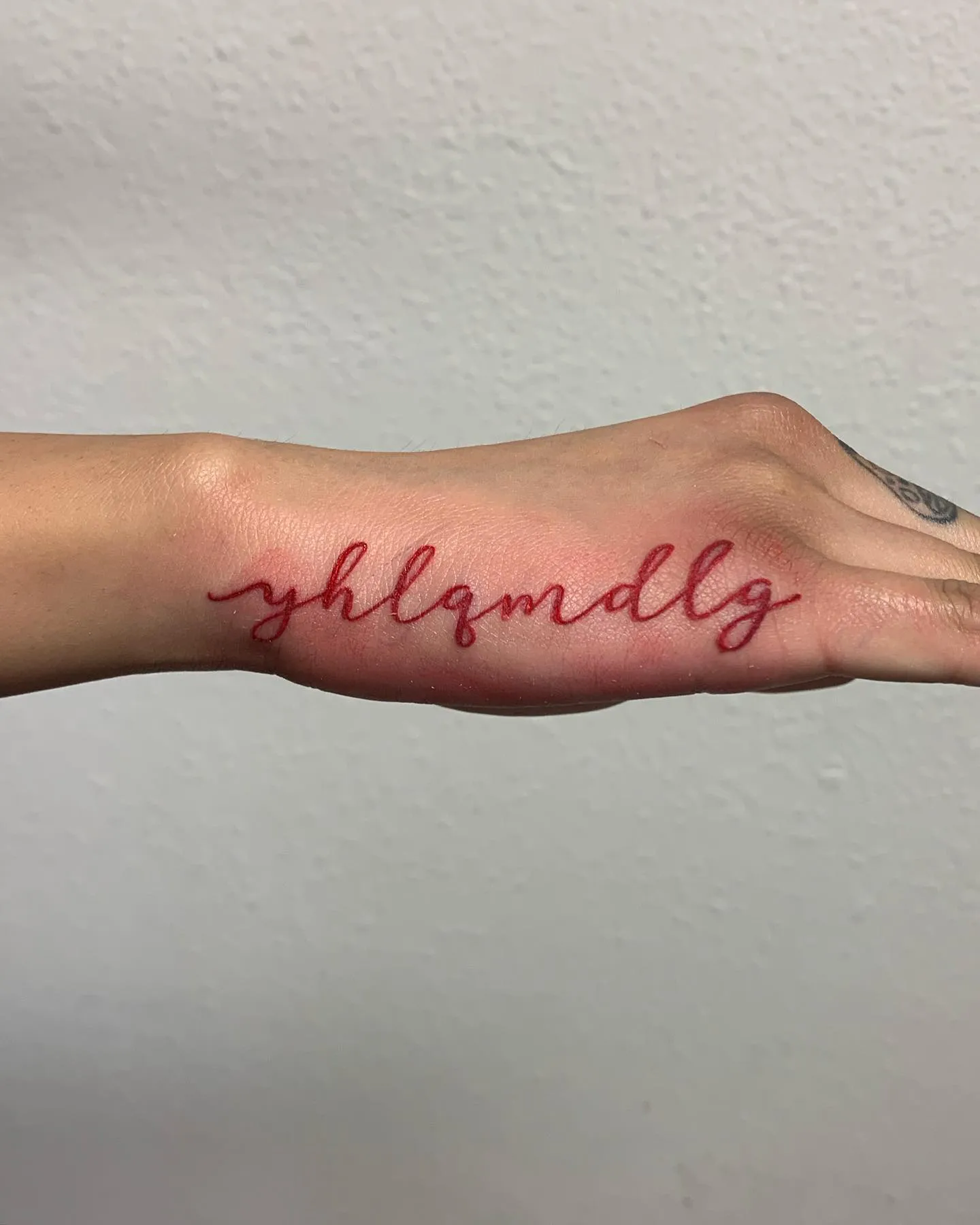 Simple Red Script Tattoo on Side of Hand