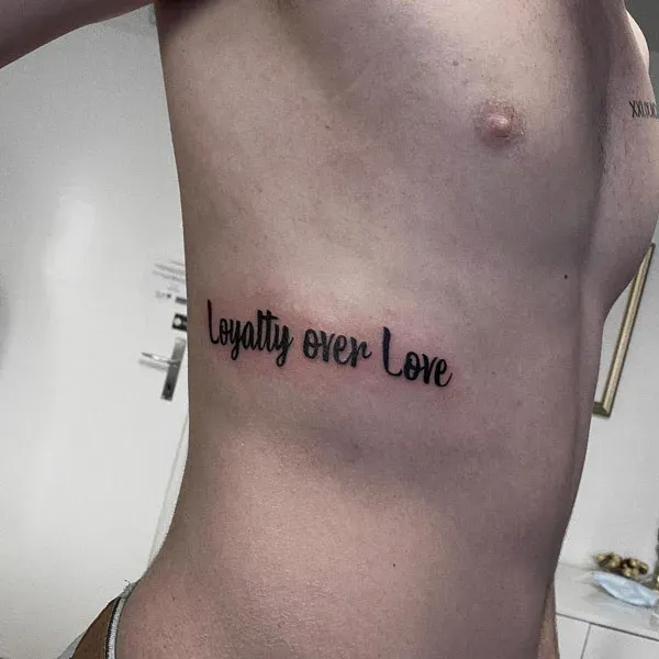 Subtle loyalty over love side torso tattoo