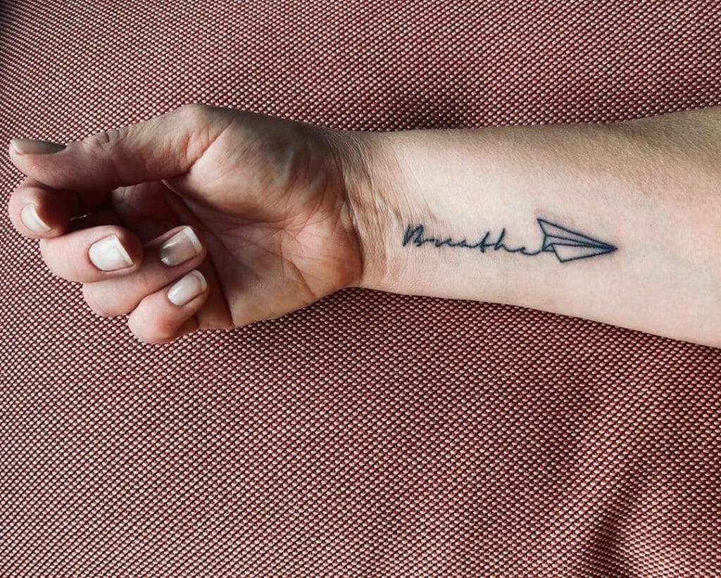 Black Ink Wrist Tattoo Just Breathe with Paper Plane Design