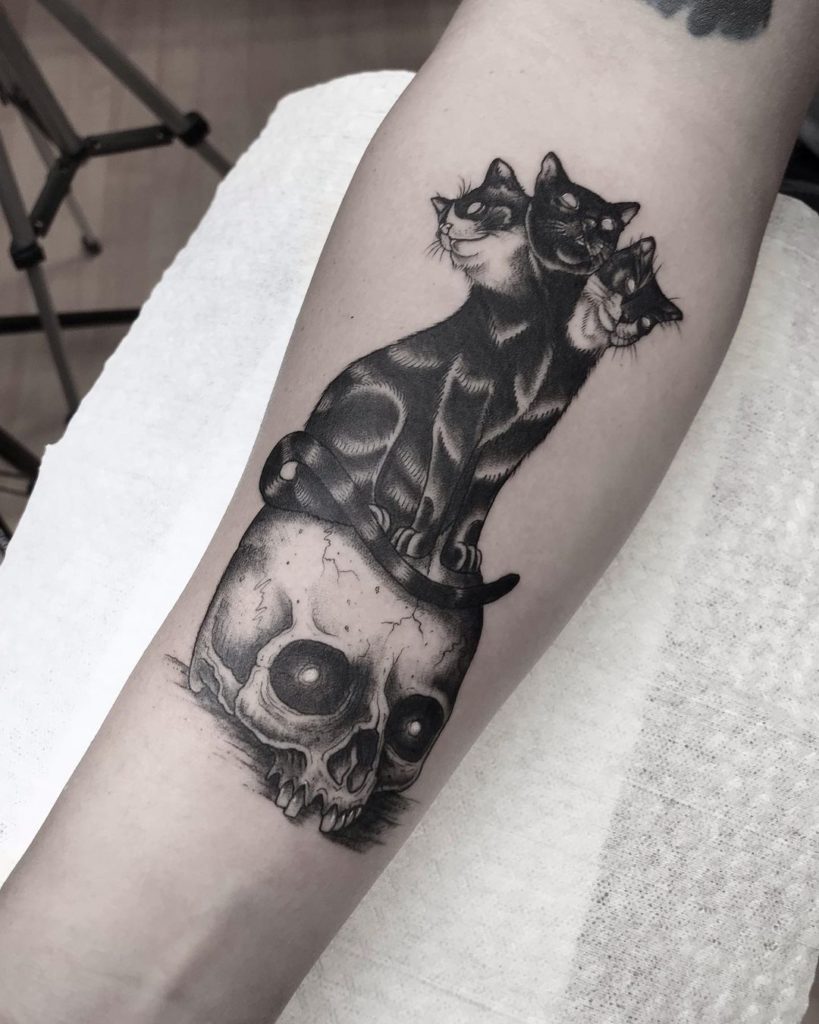 3 Headed Black Cat Standing On A Skull Tattoo Design