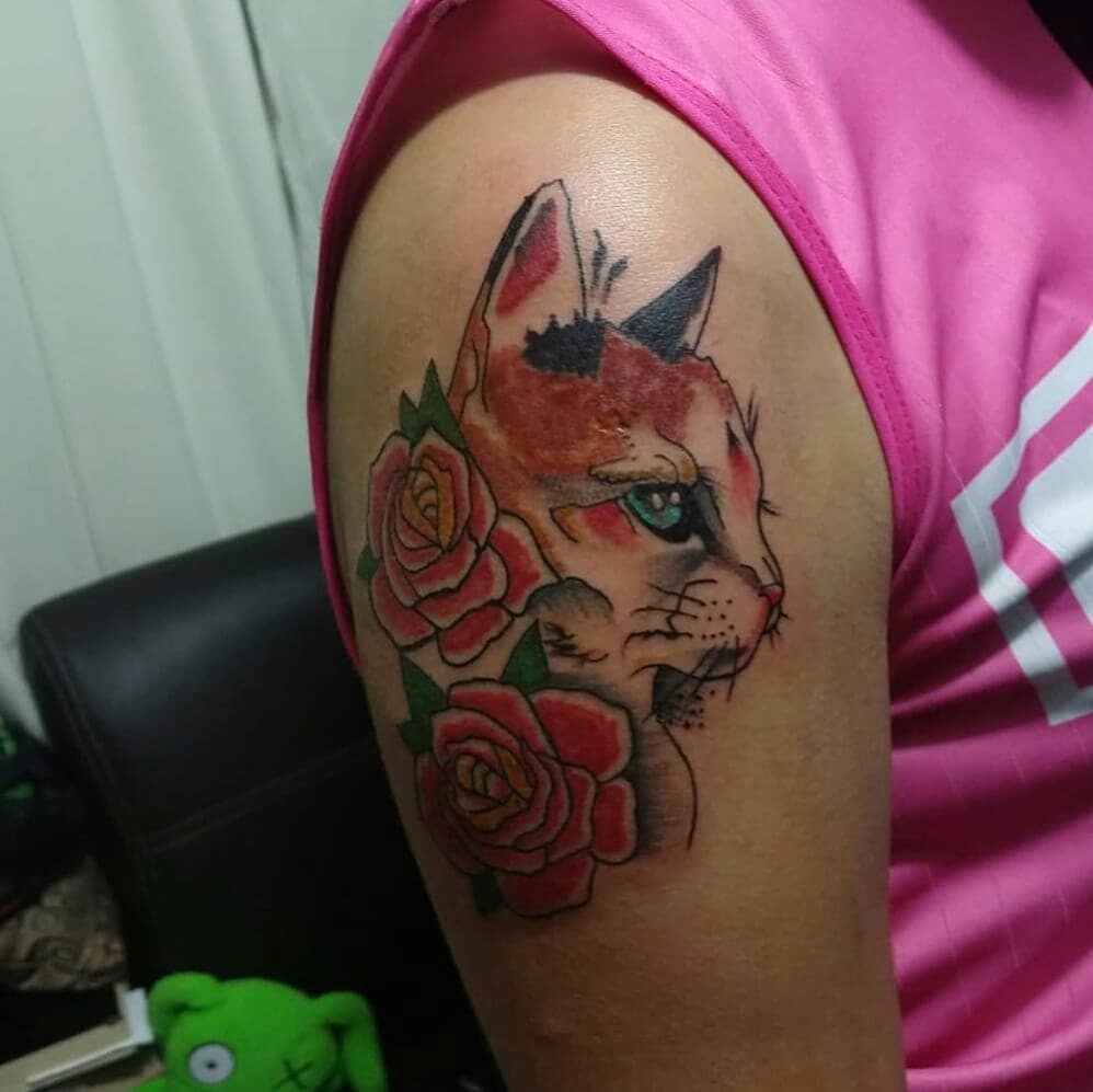Cute Cat With A Pair Of Roses Tattoo