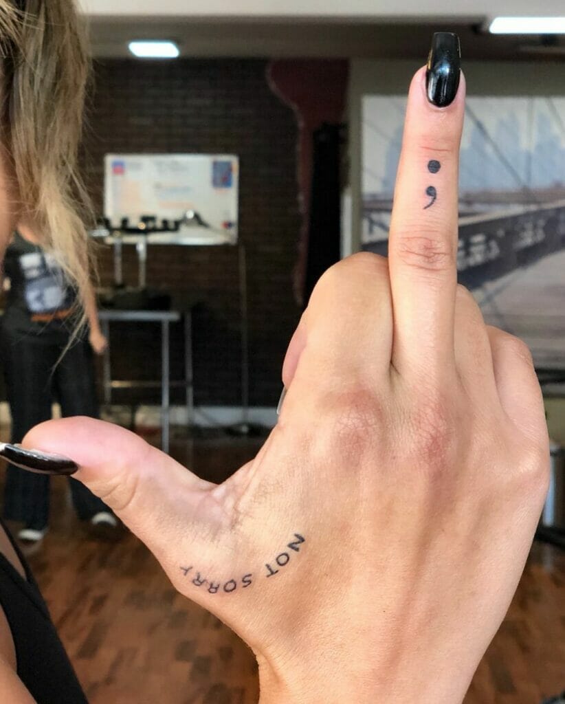 A Semi Colon Tattoo On The Middle Finger