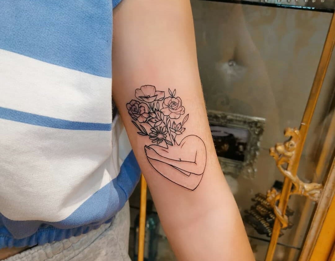 Self hug tattoo located on the upper arm minimalistic