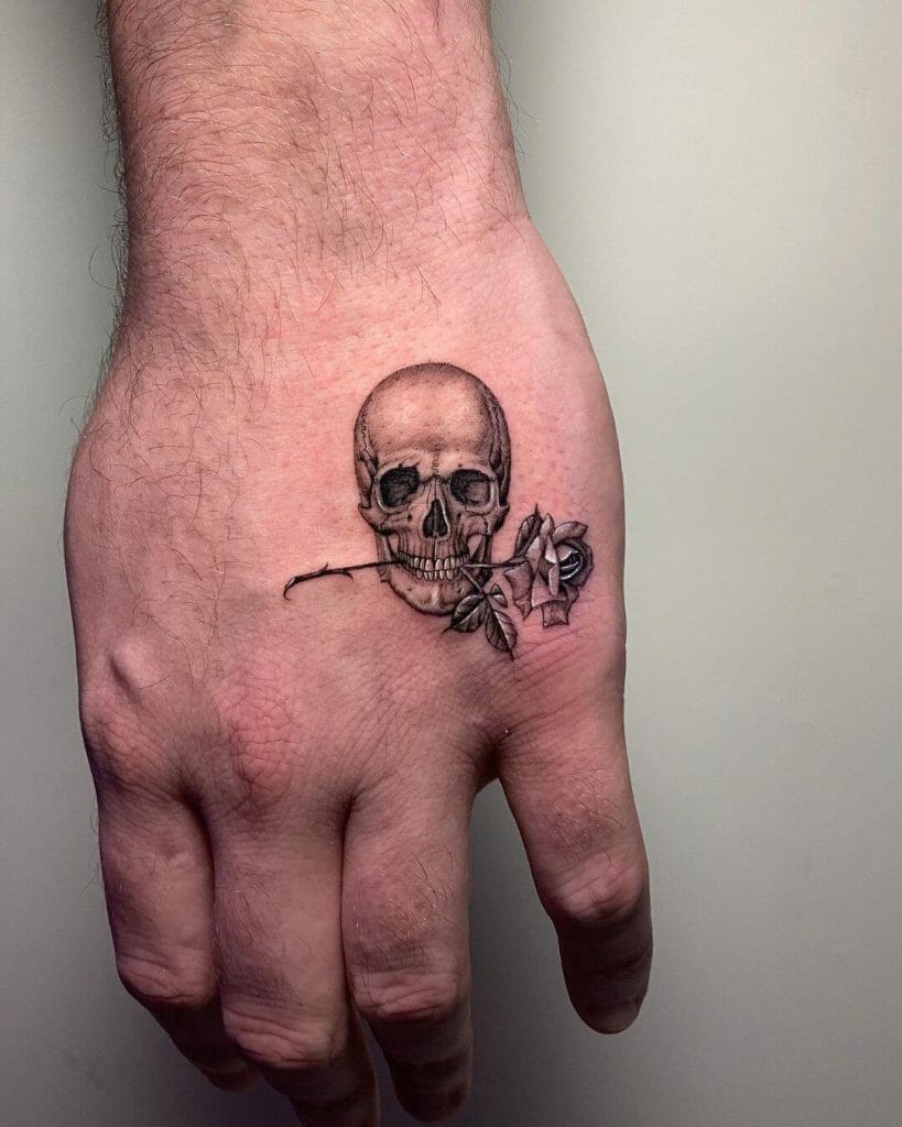 Skull Holding A Rose Between Its Teeth Tattoo Design