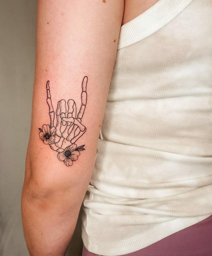 A Skull Hand Tattoo With Flowers