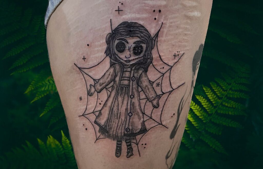 Coraline tattoo done on the upper arm cartoon style
